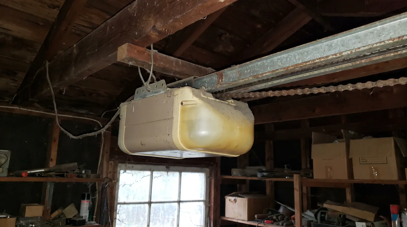Older chain-drive garage door opener mounted to the ceiling of a garage